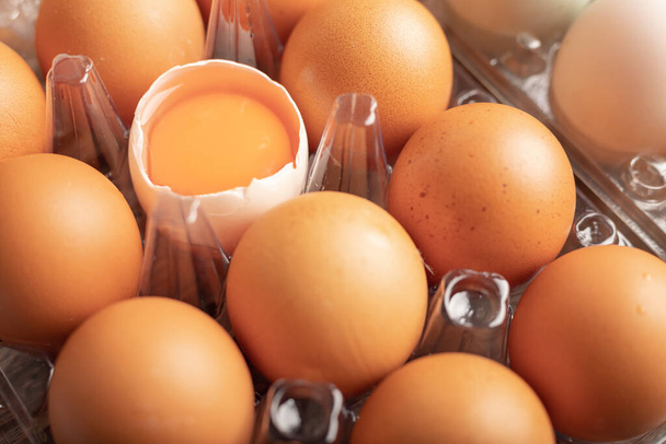 Close up broken eggs of duck in plastic box on the wooden table. Yolk in peel. Select focus shallow depth of field. - Φωτογραφία, εικόνα