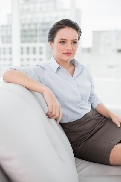 Serious well dressed young woman sitting on sofa - Foto, immagini