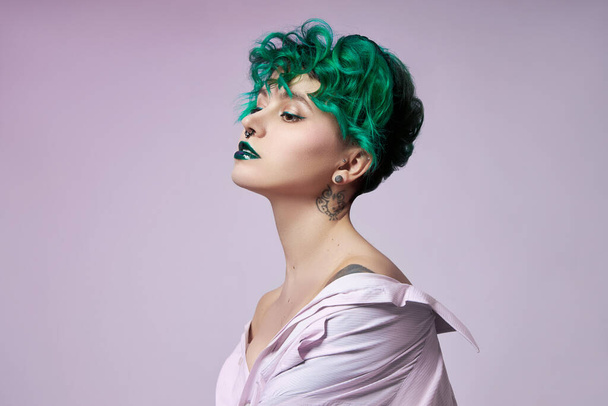 Frau mit kreativ grün gefärbten Haaren und Make-up, giftigen Haarsträhnen. Helle Farbe lockiges Haar auf dem Kopf des Mädchens, professionelles Make-up. Frau mit Tätowierung - Foto, Bild