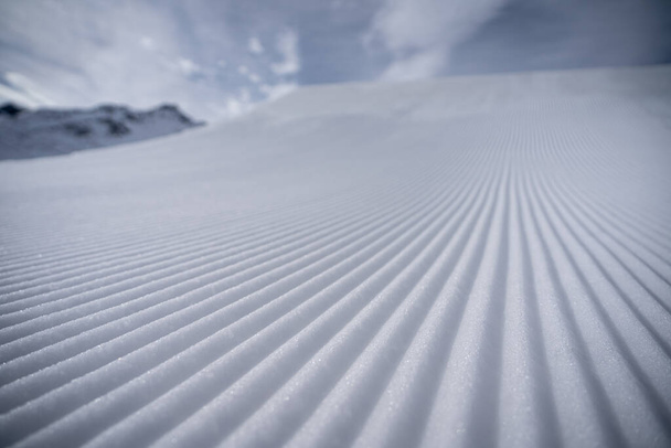 Wzór świeżo przygotowanego stoku narciarskiego przed wielkim kickerem w pro-line snowparku w St. Anton am Arlberg, Austria w słoneczny dzień. - Zdjęcie, obraz