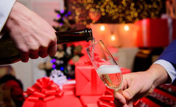 Celebrate new year with champagne. Hands pouring champagne into elegant glass christmas decorations background. Cheers concept. Last minute before new year. Drink champagne or sparkling wine - Fotó, kép