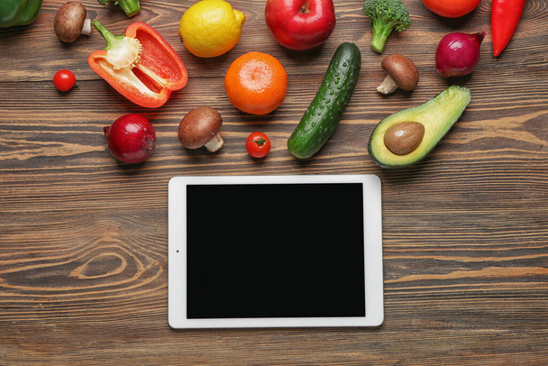 Tablet ordenador con productos saludables sobre fondo de madera
 - Foto, imagen