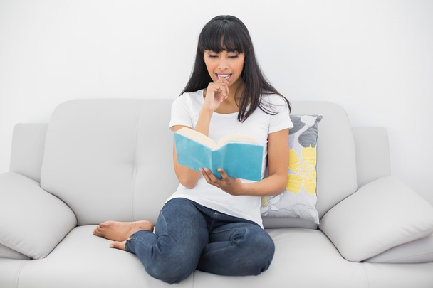 Calm dark haired woman reading a book sitting on couch - Foto, Imagem