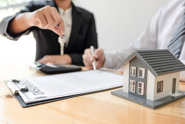 Real estate agent broker hand over the house key to the new owner after completing the signing according to agreement renting a house and buy house insurance Home insurance concept. - 写真・画像