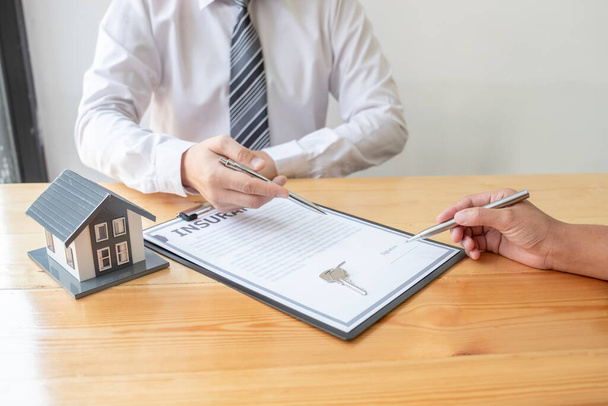 Ein Immobilienmakler mit Hausmodell spricht mit Kunden über den Kauf einer Hausratversicherung. Eigenheimversicherungskonzept. - Foto, Bild