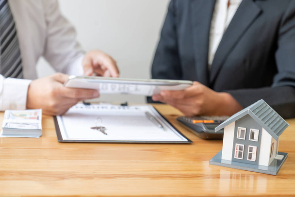 Ein Immobilienmakler mit Hausmodell spricht mit Kunden über den Kauf einer Hausratversicherung. Eigenheimversicherungskonzept. - Foto, Bild