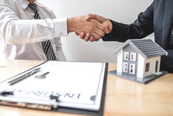 ビジネスマンやブローカーの不動産業者は、住宅保険を購入し、契約に署名するための交渉を完了した後、握手します。住宅保険の概念. - 写真・画像