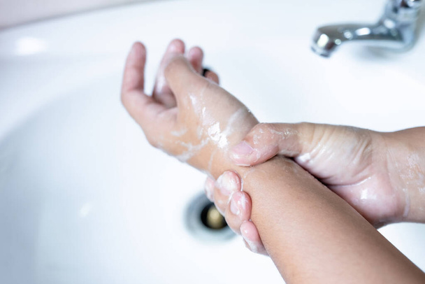 Las manos de la mujer se lavan las manos con jabón, se limpian las manos en la bañera con jabón, higiene personal
. - Foto, Imagen