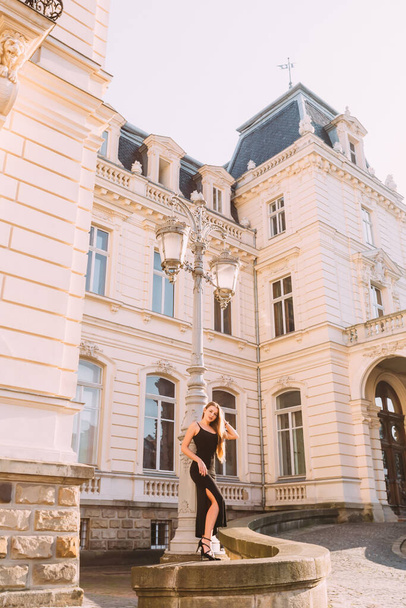 bâtiment avec belle architecture et fille en robe noire près de lanterne de rue. - Photo, image