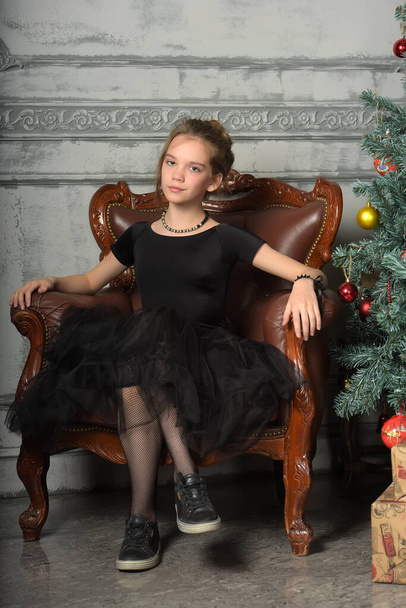 portrait of a beautiful pensive girl in black near the Christmas tree at Christmas, no mood, sad - Valokuva, kuva