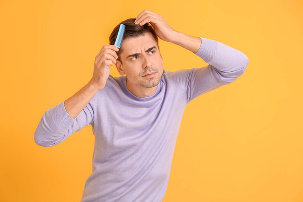 Handsome young man combing hair on color background - Photo, Image