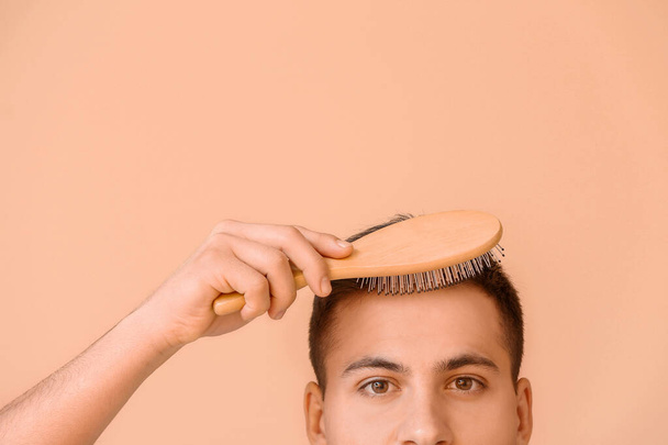 Bello giovane uomo spazzolatura capelli su sfondo di colore
 - Foto, immagini