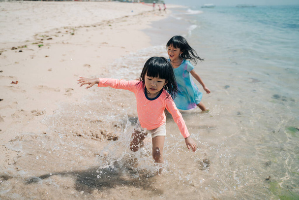 two little Asian girls playing on the beach - Photo, image
