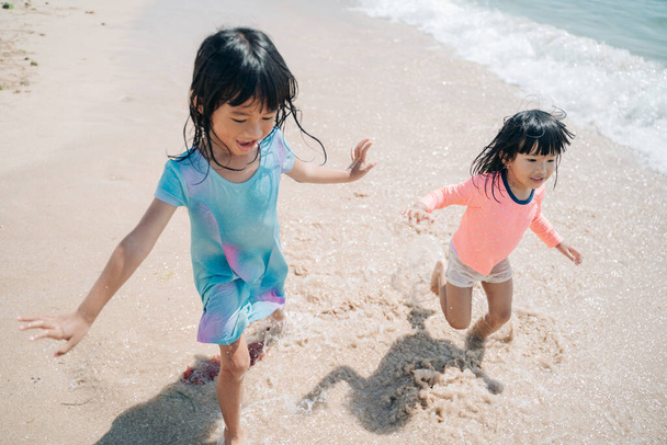 two little Asian girls playing on the beach - Foto, imagen