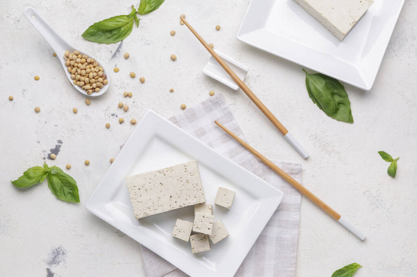 Teller mit leckerem Tofu-Käse und Sojabohnen auf weißem Hintergrund - Foto, Bild