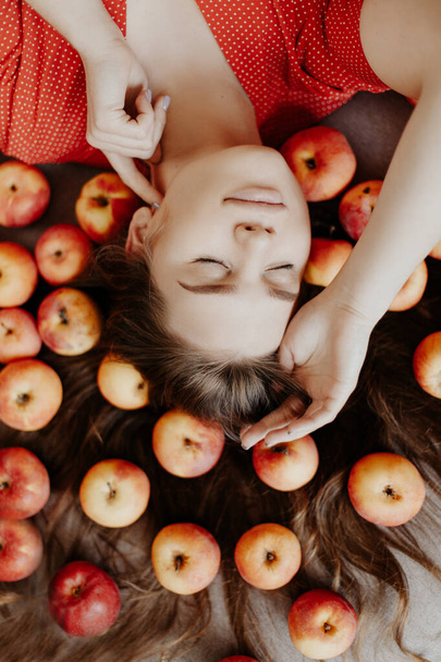 Beautiful girl in a red dress with apples on her hair - Foto, Bild