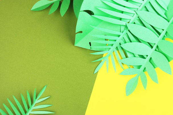 various tropical leaves on a yellow and green background, top view. exotic background with paper green leaves - Photo, image
