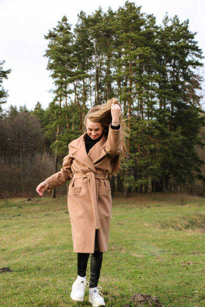 красивая девушка, блондинка с длинными волосами, прогулки весной возле леса в коричневом пальто., спокойствие и свобода
 - Фото, изображение