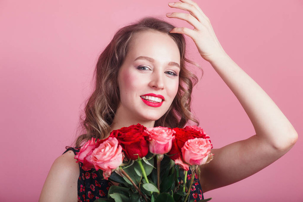Happy laughing romantic woman holding flowers on pink background. Beauty woman with roses - Фото, изображение