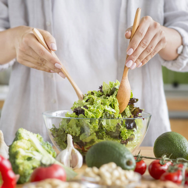 Жінка готує здорову їжу на кухні і змішує свіжий салат
 - Фото, зображення