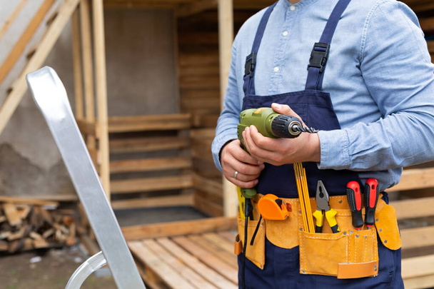 Close up picture of construction worker holding electric drill, renovation at home - Foto, afbeelding