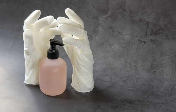Ένα ζευγάρι ιατρικά γάντια, υγρό σαπούνι. - Φωτογραφία, εικόνα