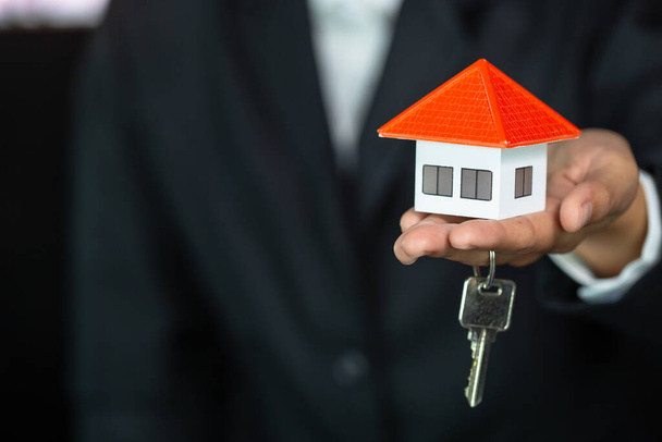 Πορτοκαλί σπίτι οροφής Κρατώντας το κλειδί και τα σπίτια από businessmen.House στα χέρια των επιχειρηματιών ή των πωλήσεων representive.Agents δίνουν το σπίτι και το σπίτι κλειδιά για τους πελάτες.. - Φωτογραφία, εικόνα