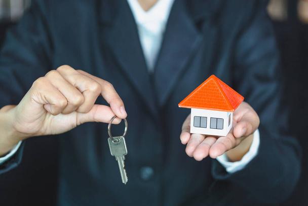 Az ingatlanügynökök tartják otthon a kulcsokat az ügyfeleknek. Ötletek ingatlan, költöztető házak vagy bérbeadása ingatlanok.Üzletemberek elkapni a kulcsot.Otthoni kereskedelem.Van hely a szöveges bejegyzés.. - Fotó, kép