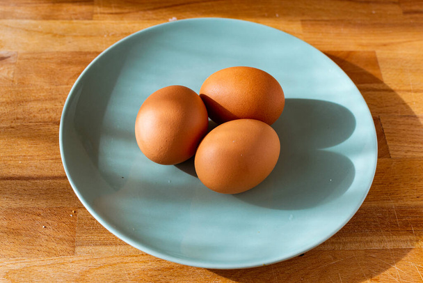 три свежих яйца на тарелке
 - Фото, изображение