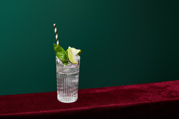 Wysoki kąt widzenia mojito z lodem, miętą, wapnem i pasiastą słomką do picia ze szkła Collins izolowane na zielono - Zdjęcie, obraz