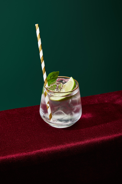 Hochwinkelblick auf altmodisches Glas mit goldenem Rand mit Mojito und gestreiftem Trinkhalm isoliert auf Grün - Foto, Bild