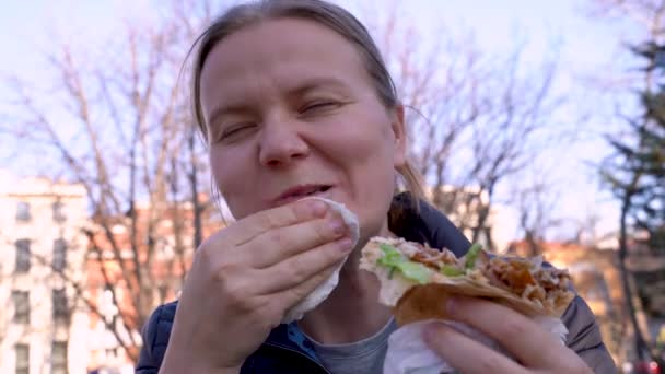 Nuori valkoihoinen nainen syö nälkäisesti pikaruokaa
. - Materiaali, video