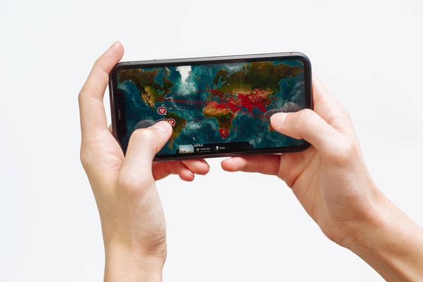 Samara Russia - 04.05.2020: Hands holding a smartphone Iphone 11 with Plague Inc: Evolved game on display screen, Illustrative Editorial. - Foto, Imagen