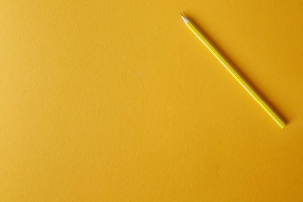 Желтый карандаш лежит на ярко-желтом фоне, макрофотография
. - Фото, изображение