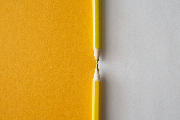 Yellow colored pencil lying on a bright yellow and white background, macro photography. - Фото, зображення