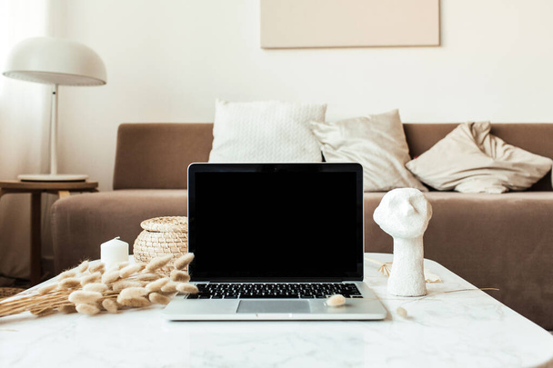 Εμπρόσθια όψη της λευκής οθόνης laptop σε μαρμάρινο τραπέζι με φύλλα καλάμων, προτομή. Χώρος εργασίας γραφείου στο σπίτι. - Φωτογραφία, εικόνα
