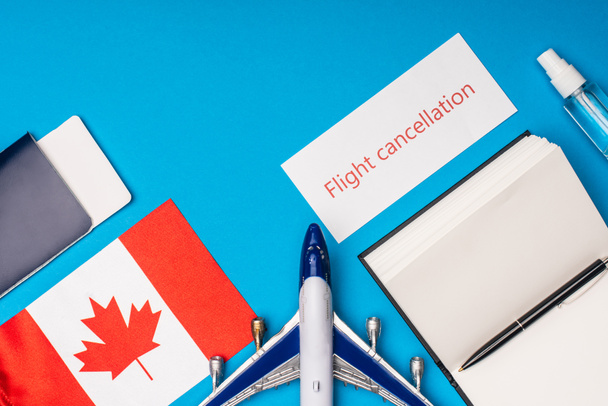 Widok z góry samolotu zabawki, karty z odwołania lotu i flagi Kanady na niebieskim tle - Zdjęcie, obraz