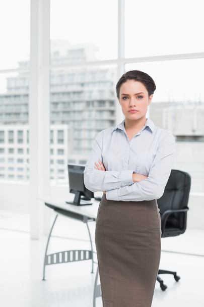 Elegant businesswoman standing with arms crossed in office - Foto, Imagem