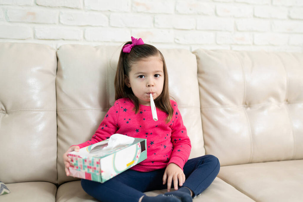 Ritratto di una bella bambina che si sente male e usa un termometro per controllare la febbre a casa
 - Foto, immagini