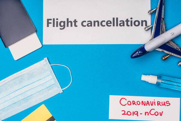 Vista superior de cartões com cancelamento de voo e coronavírus 2019-nCov lettering perto de máscara médica, cartão de crédito e avião de brinquedo na superfície azul
 - Foto, Imagem