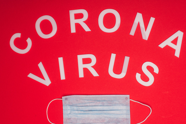 医学マスクとコロナウイルスのレタリングの上ビュー赤の背景 - 写真・画像