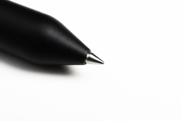 Una macro toma de la punta de escritura con una porción del cañón de un moderno bolígrafo negro aerodinámico sobre fondo blanco
. - Foto, Imagen