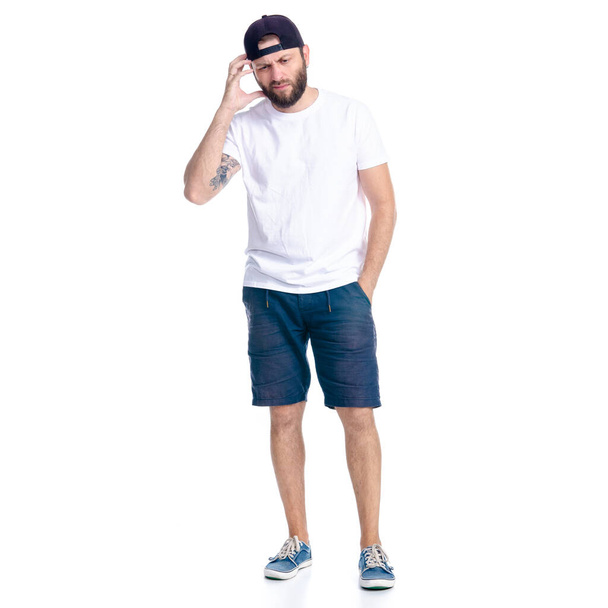 Man in shorts and cap standing thinking nervous - Foto, afbeelding