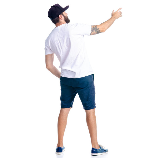 Homem de shorts e boné em pé olhando mostrando apontando
 - Foto, Imagem