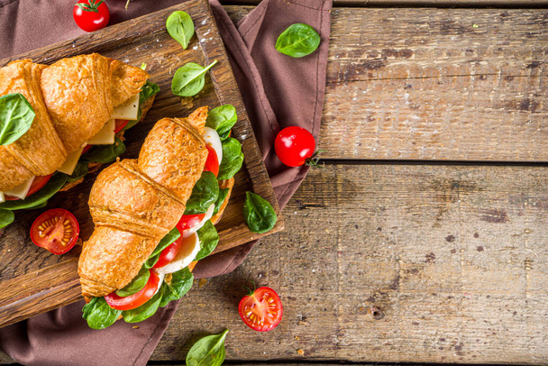 Hausgemachte Croissant-Sandwiches mit Schinken, Käse, frischem Gemüse und Kräutern,  - Foto, Bild