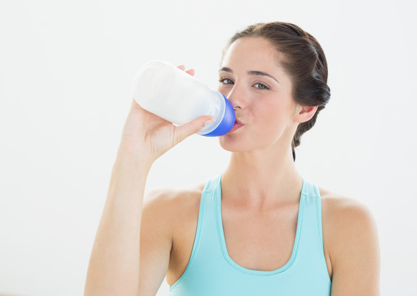 Portrait of a sporty woman drinking water - Photo, Image