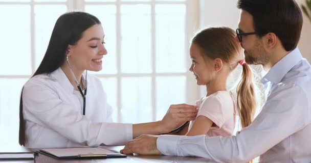 Mosolygó barátságos női gyermekorvos hallgat szívverés boldog óvodás gyerek. - Felvétel, videó