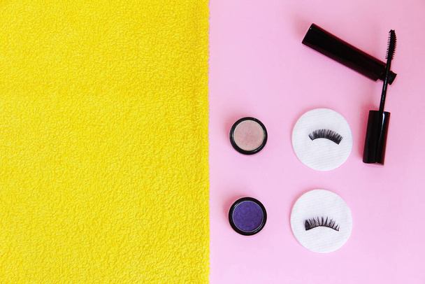 kosmetika, krém, řasenka, bavlněné podložky na žlutém a růžovém pozadí - Fotografie, Obrázek