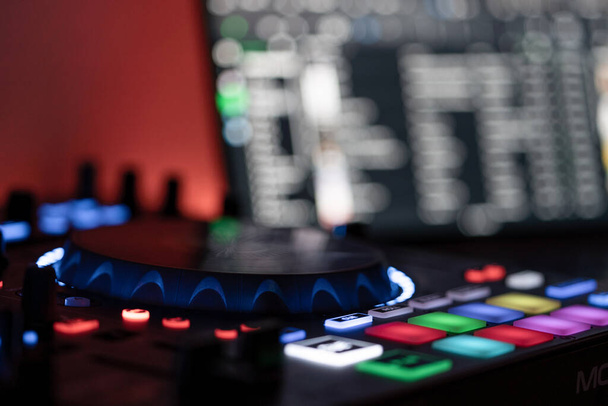 Vista lateral de un controlador DJ con ordenador portátil DJ en un fondo borroso
 - Foto, Imagen