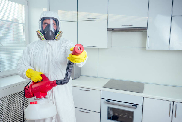 pest control worker standing with sprayer in kitchen - Foto, imagen
